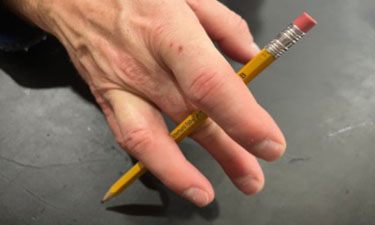 Hand holding pencil with pencil intertwined in fingers