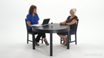 Two people talking at a round table with a laptop and notebook in front of a white background for medbridge.