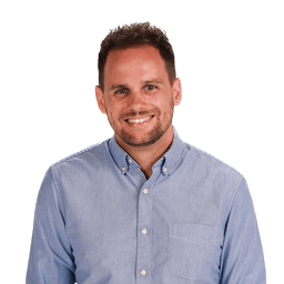 Man smiling in a light blue shirt with short hair and beard, standing against a white background (medbridge).