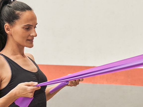 User exercises with a purple resistance band fixed to a pillar in the medbridge app.