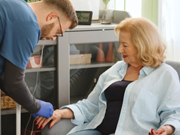A medbridge healthcare worker measures a woman's blood pressure in a living room.
