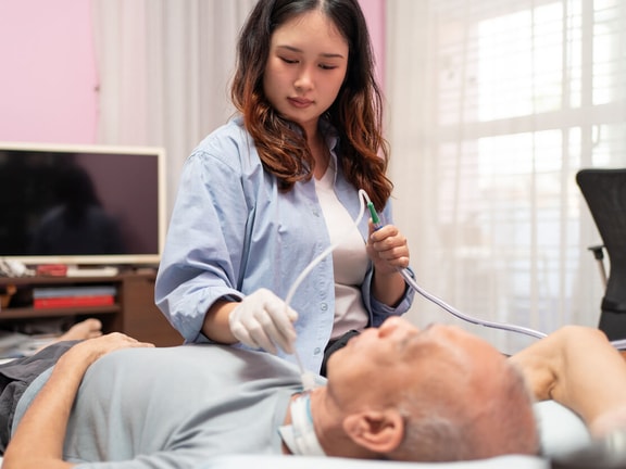 Trained caregiver provides suctioning for a tracheostomy patient as part of a tracheostomy nursing care plan.