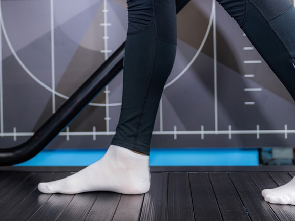 Person with white socks and black pants walking on treadmill; graphic pattern background. #medbridge.