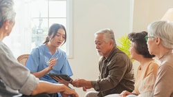 A healthcare professional in blue scrubs leads family training in rehabilitation, guiding caregivers through patient care strategies.