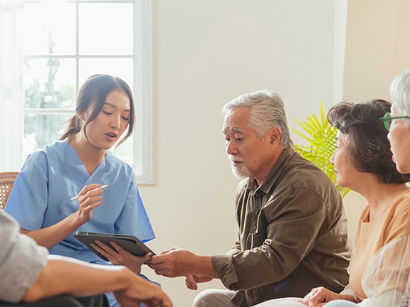 A healthcare professional in blue scrubs leads family training in rehabilitation, guiding caregivers through patient care strategies.