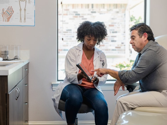 Clinician and patient review a digital treatment plan on a tablet, illustrating hybrid care in a rural clinic setting.