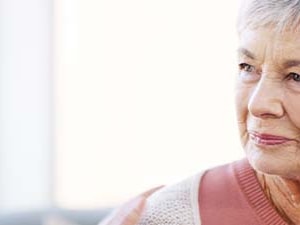 Two women, one younger and blonde, one older with gray hair, are chatting indoors.