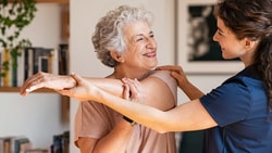 Clinician uses improv-based mirroring to build trust with an older adult during a supportive shoulder stretch session.