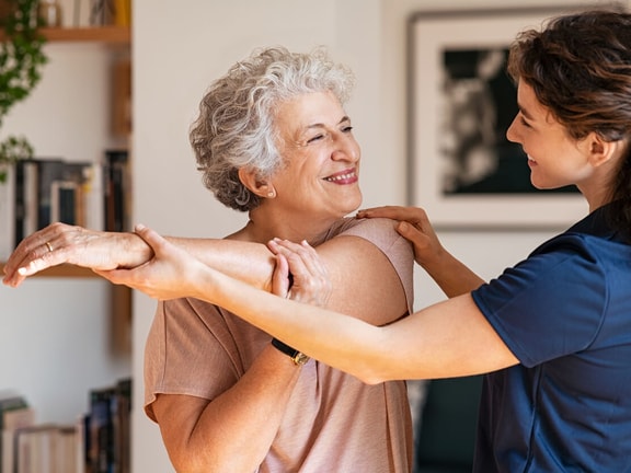 Clinician uses improv-based mirroring to build trust with an older adult during a supportive shoulder stretch session.