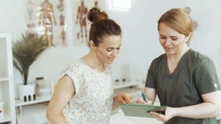 Healthcare professional reviewing digital patient feedback data on a tablet to improve clinical quality.