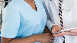 A nurse and a doctor examine a tablet in the hospital.