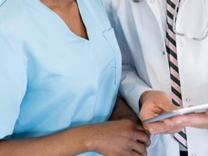 A nurse and a doctor examine a tablet in the hospital.