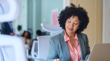 A woman reviews a colorful chart on digital healthcare at her desk with a laptop, representing medbridge.