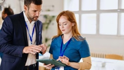 Healthcare administrator and clinician reviewing remote therapeutic monitoring (RTM) policy update on tablet in clinic setting