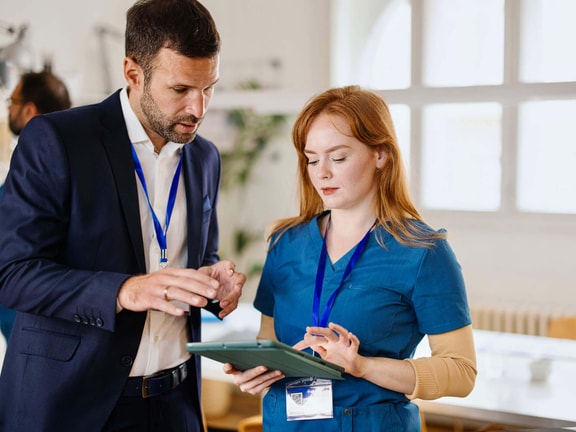 Healthcare administrator and clinician reviewing remote therapeutic monitoring (RTM) policy update on tablet in clinic setting