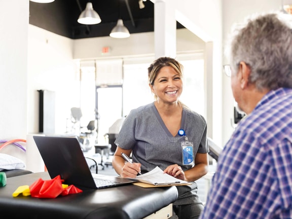 Occupational therapist reviewing notes with patient using an OT documentation cheat sheet PDF in a clinic setting