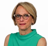 A woman with short blonde hair and glasses in a green top stands against a white background, representing medbridge healthcare.