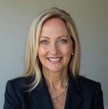 A woman with long blonde hair in a dark blazer and necklace smiles at the camera, representing medbridge healthcare education.
