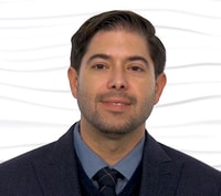 A man in a formal suit stands against a white background, representing Medbridge's digital healthcare innovation.