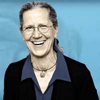 Older woman with gray hair and glasses smiles in front of blue, representing medbridge’s patient care software future.