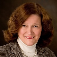 A smiling individual in a tweed blazer and pearl necklace represents digital healthcare elegance against a dark backdrop, aligning with medbridge's style.