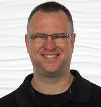 A knowledgeable man in a black polo stands, representing medbridge's expertise in patient care software.