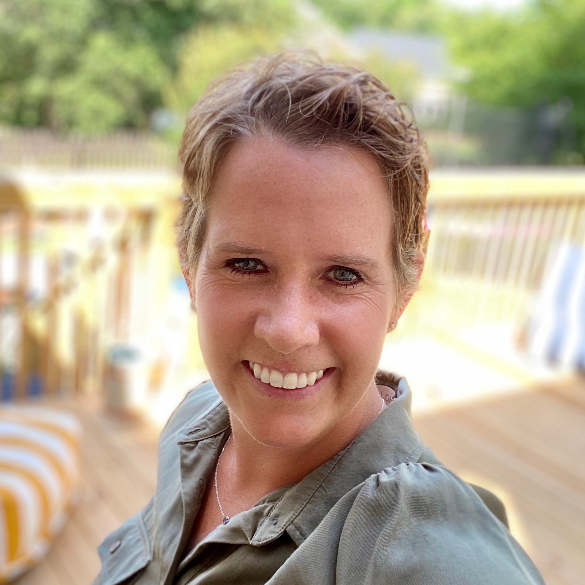 A person with short hair smiles on a sunlit deck, capturing the essence of medbridge's modern digital healthcare innovations.