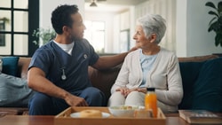 A healthcare worker talks with an older woman at home near a breakfast tray, discussing medbridge digital care.