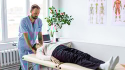 Clinician performing the Dix-Hallpike test to assess positional vertigo while supporting a patient’s head on a treatment table.