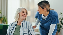 Home health professional engaging with an older adult patient as part of compliant, patient-centered home care.