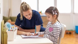 Occupational therapist helping a child with handwriting to support motor skills and executive functioning.