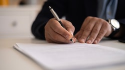hand holding pen and writing on paper - patient specific functional scale