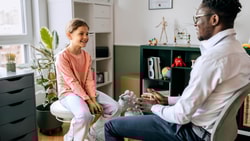 Clinician speaking with a child during evaluation, representing pediatric traumatic brain injury (TBI) assessment and rehabilitation.