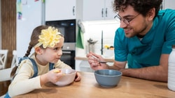Feeding therapist supporting pediatric tube weaning readiness during a guided mealtime with a young child