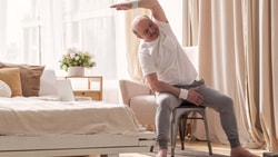 Older adult performing a seated side-bend exercise, illustrating seated balance and postural control assessed by the Sitting Balance Scale.
