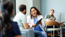 Clinician discussing care progress with a patient using a tablet to support patient-reported outcomes and remote therapeutic monitoring.