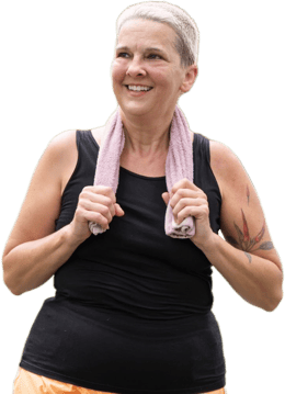 Smiling older woman with gray hair and a pink towel around her neck stands outdoors, reflecting hybrid care benefits with medbridge.