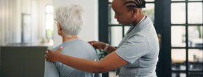 A healthcare worker uses medbridge software to check an older adult’s back and shoulders in a room.