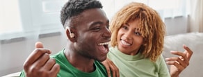 A smiling man with a hearing aid and a woman chat on a couch about medbridge healthcare training.
