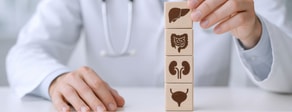 A person stacks wooden blocks showing organ icons, symbolizing digital healthcare's role in medbridge healthcare education.