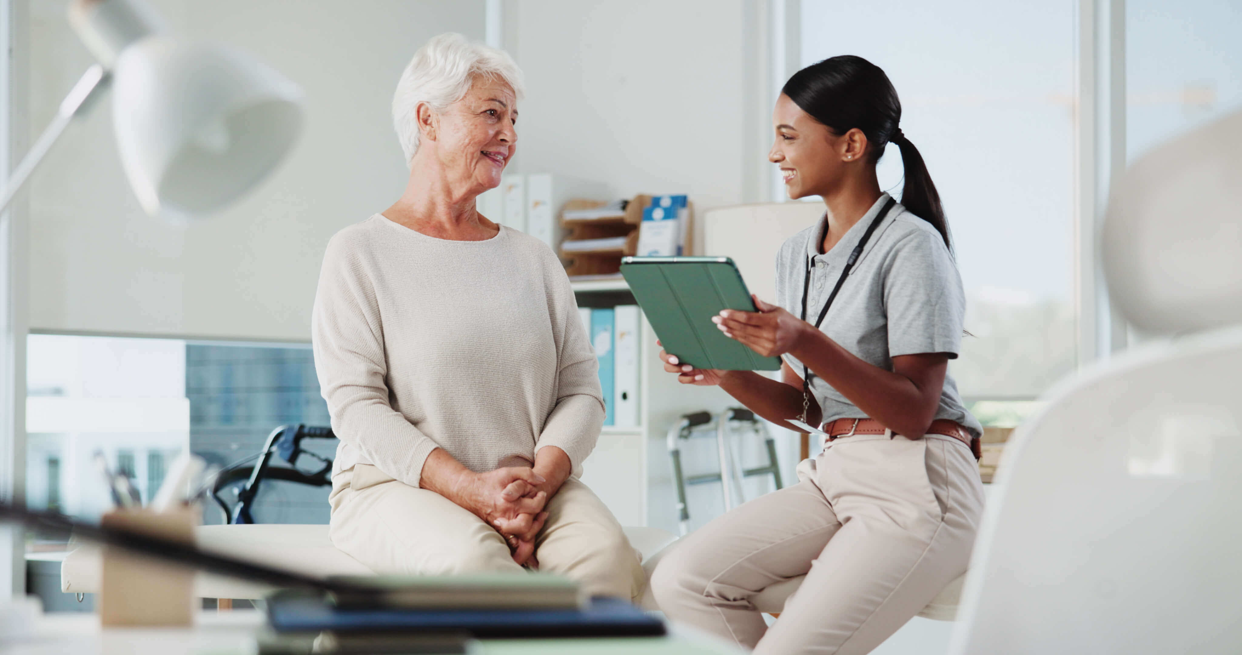Clinician using tablet to discuss remote therapeutic monitoring with an older patient during a clinic visit.