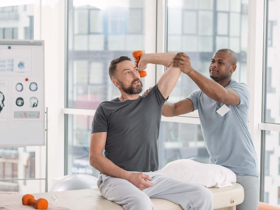 Physical therapist helping a patient with weighted deltoid facilitation after shoulder arthroplasty surgery.