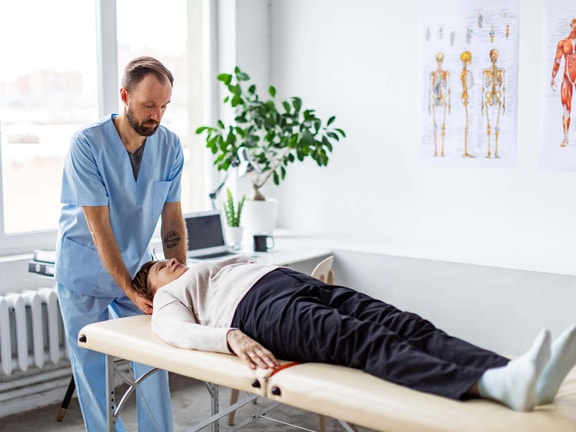 Clinician performing the Dix-Hallpike test to assess positional vertigo while supporting a patient’s head on a treatment table.