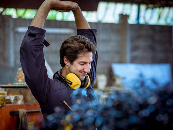 Industrial athlete stretching arms overhead during warm-up to support industrial injury prevention and reduce musculoskeletal strain.
