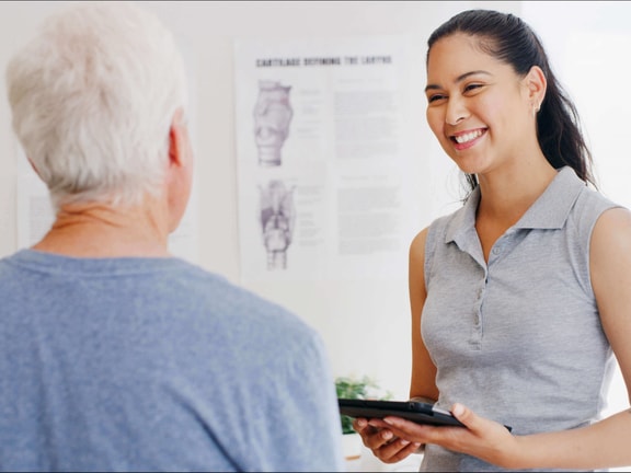Clinician discussing remote therapeutic monitoring (RTM) and reimbursement updates with older patient in clinic