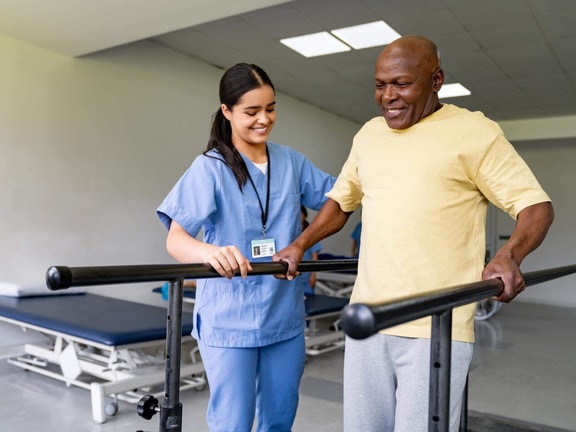 Physical therapist assisting patient with gait training on parallel bars in outpatient rehabilitation clinic