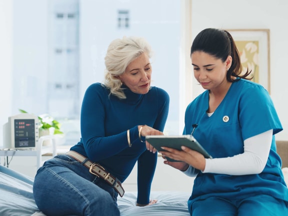 A clinician and patient review data on a tablet in a hospital setting, highlighting modern patient outcomes.