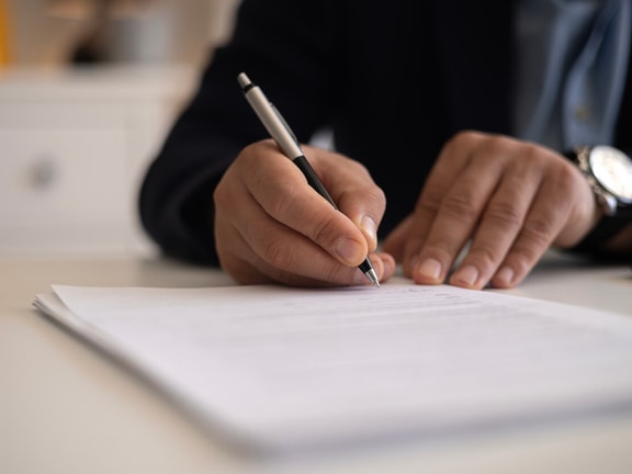 hand holding pen and writing on paper - patient specific functional scale
