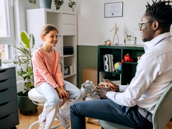 Clinician speaking with a child during evaluation, representing pediatric traumatic brain injury (TBI) assessment and rehabilitation.