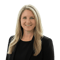 A woman with long blonde hair in a black blazer smiles at the camera, representing innovation in digital healthcare at medbridge.